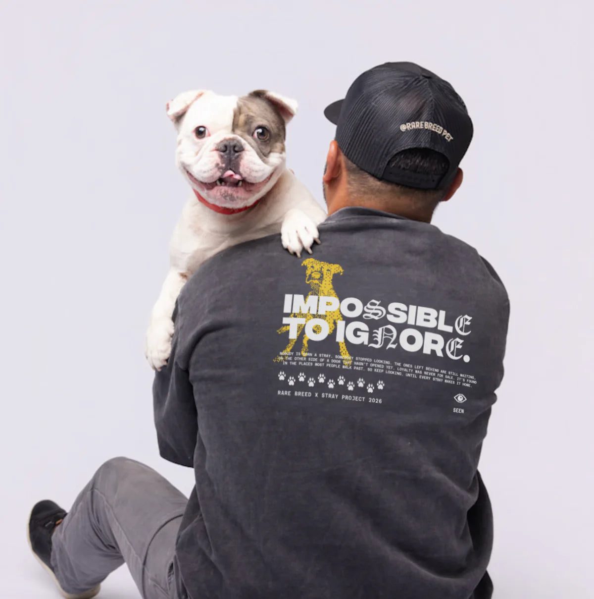 Frank holding Chini over his shoulder while wearing the black Impossible to Ignore SEEN crewneck.